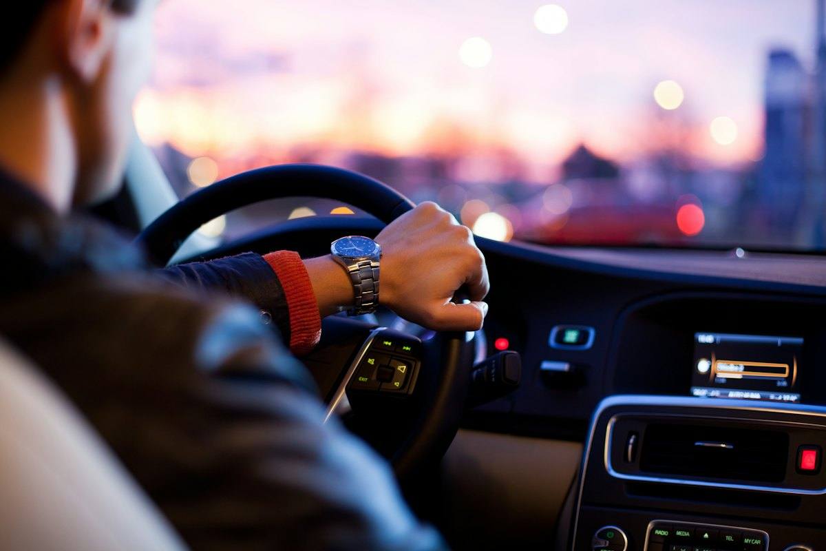 Conductor al volante de su auto durante el atardecer