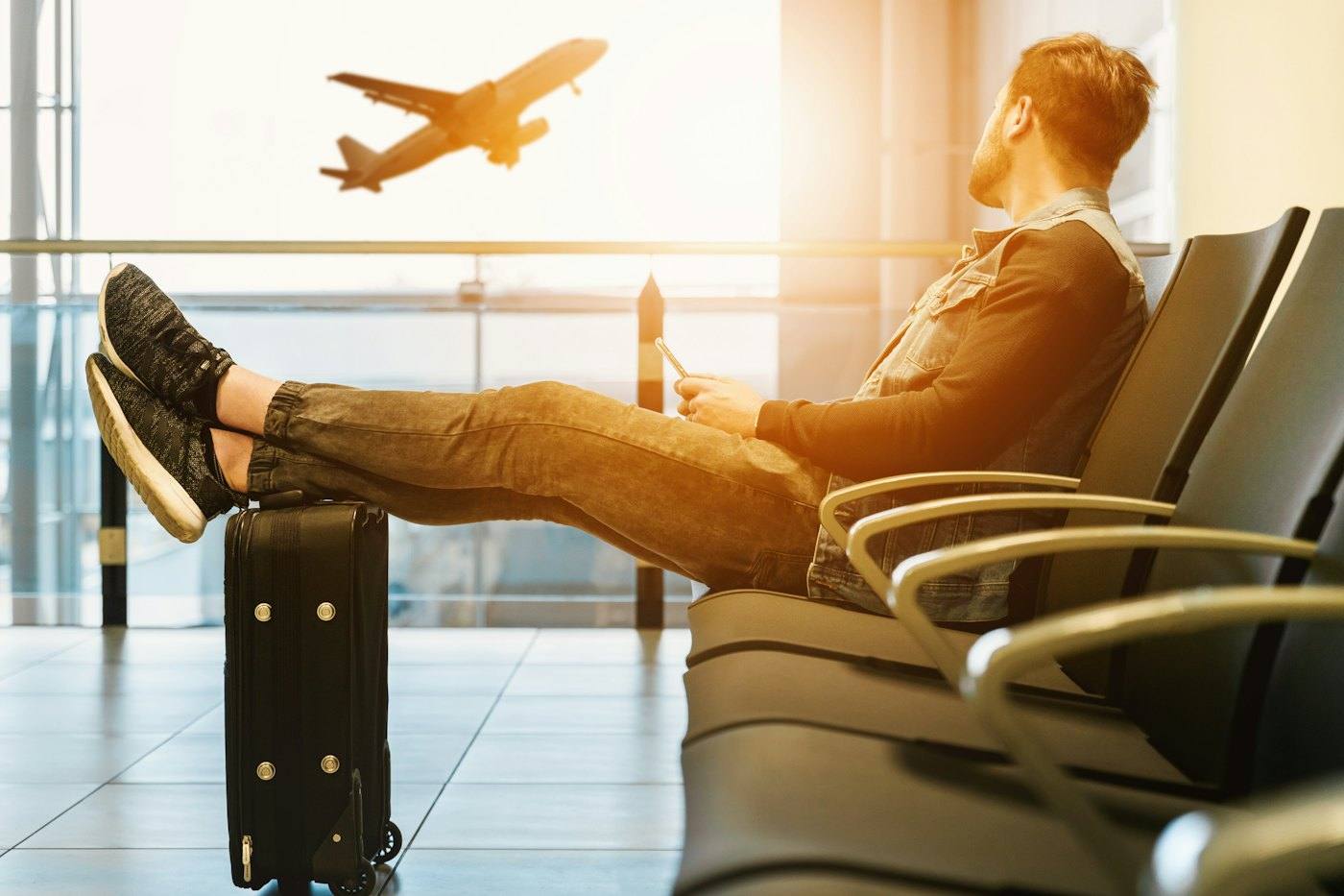 Viajero relajado en una sala de aeropuerto mientras despega un avión